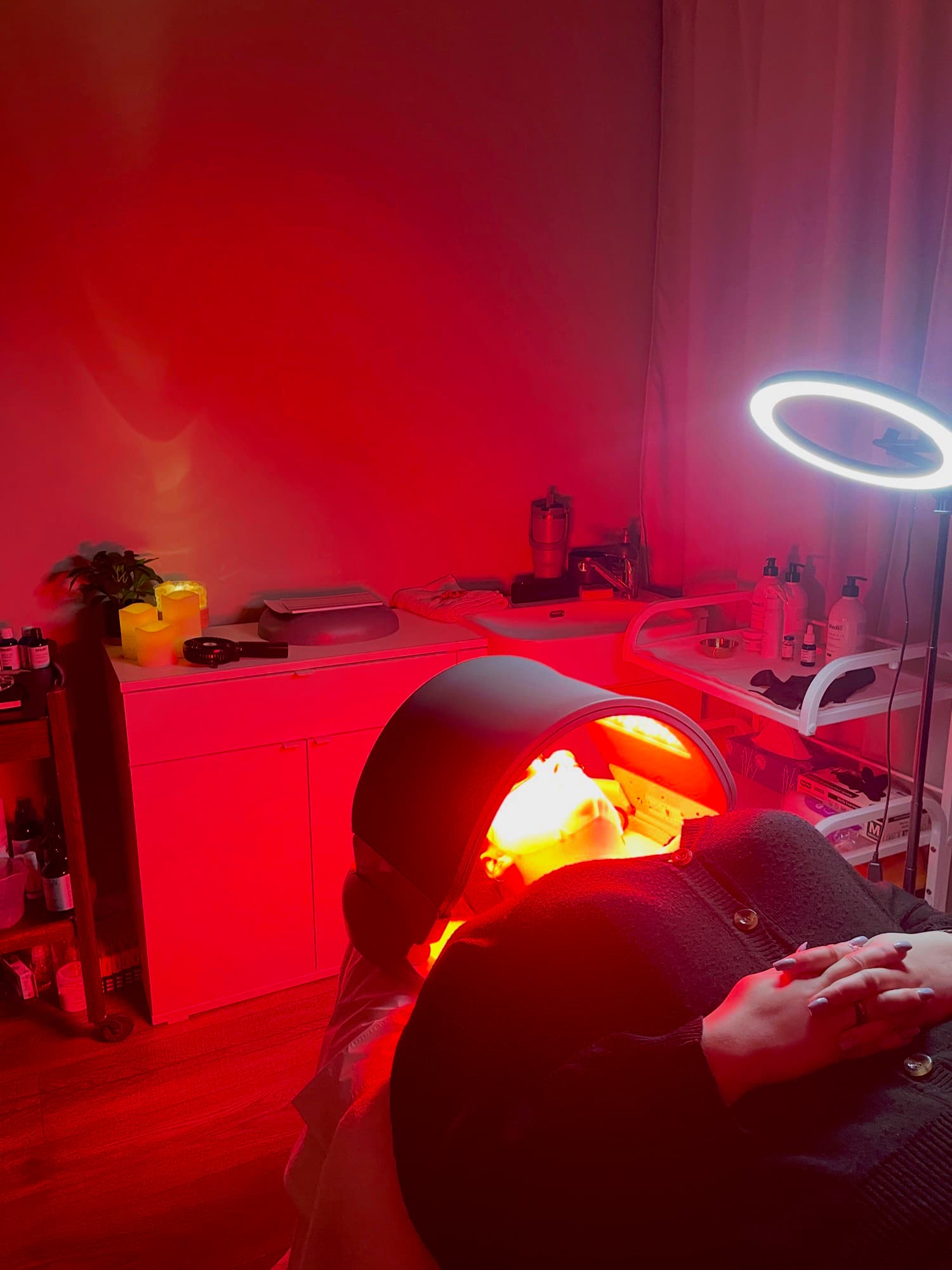 Client relaxing under the Dermalux LED canopy at Fresh Faced, bathed in red light therapy.